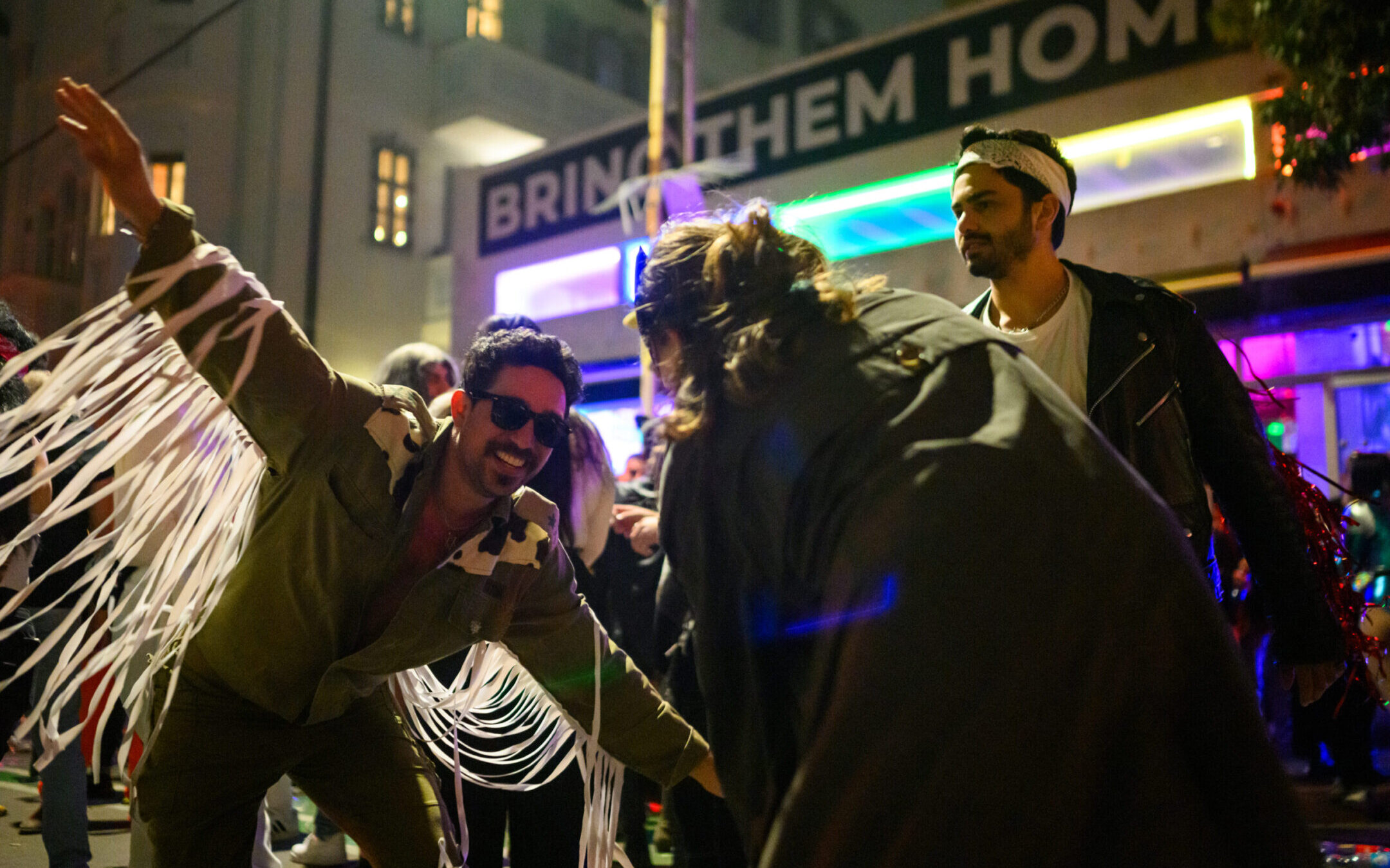 Eyal Lasry, 32, dressed as a cowboy/IDF soldier dances during Purim celebrations into the early hours of the morning near a large “Bring Them Home Now” banner on March 24, 2024 in Tel Aviv. (Alexi J. Rosenfeld/Getty Images)