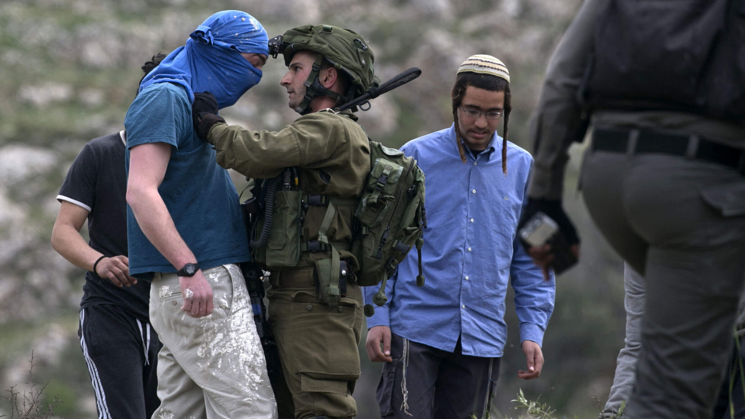 An Israeli soldier scuffles with a masked Israeli settler while trying to remove him from the area of a protest by Palestinians to mark Land Day, in the village of Madama in the Israeli occupied West Bank, March 30, 2017.