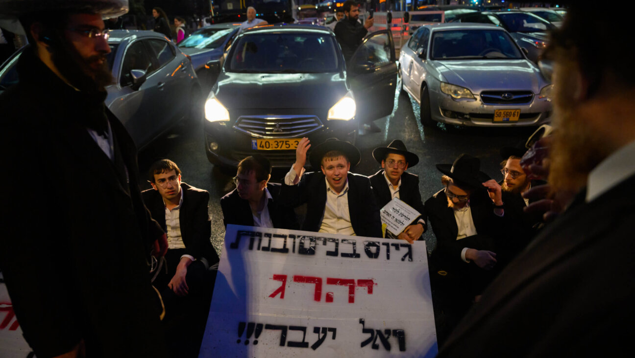 Haredi boys and men sit in front of traffic during a protest against the expiration of a law preventing them from being drafted into the IDF, March 18 in Jerusalem. 