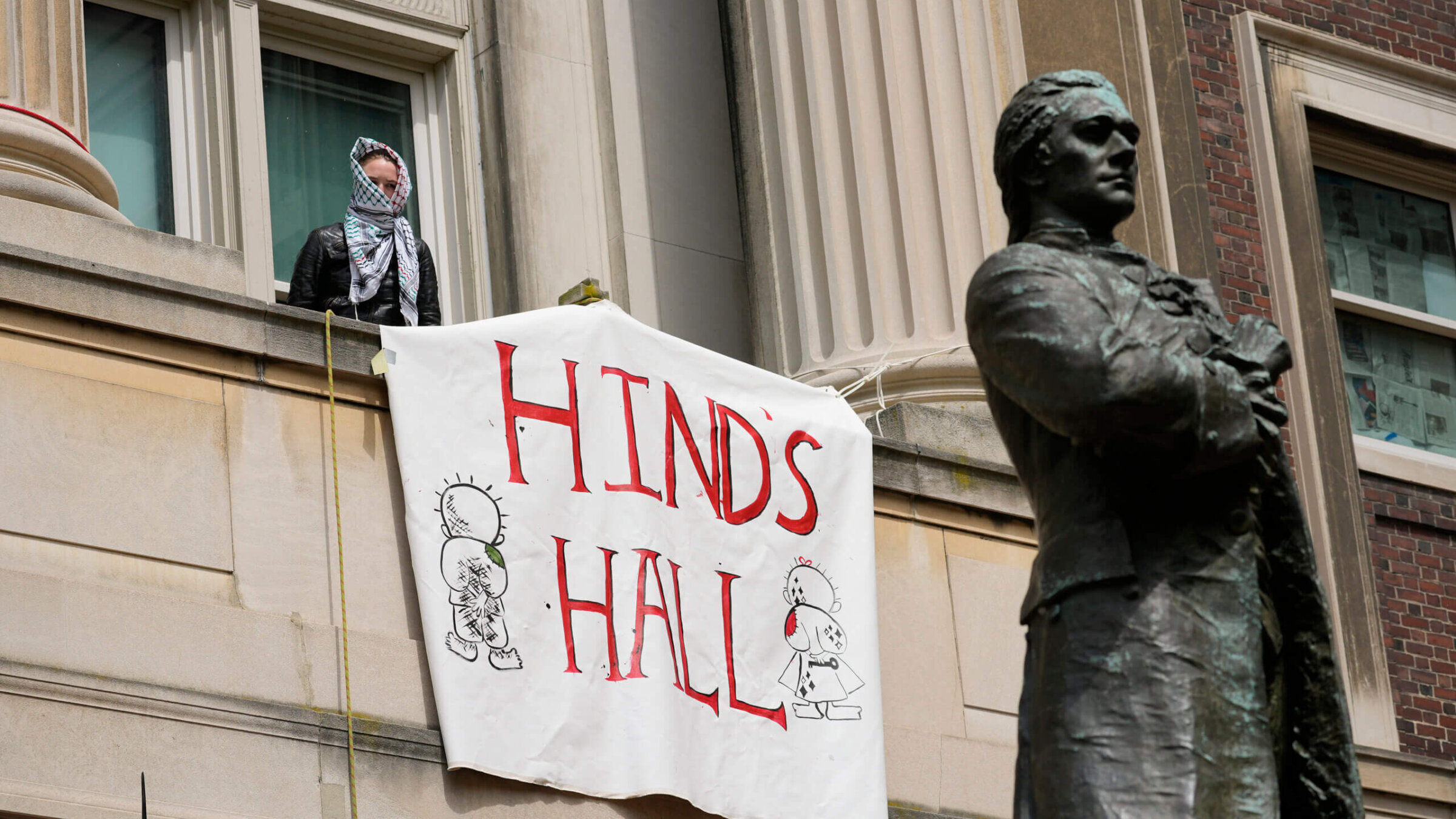 A student protester leans out a window of Hamilton Hall on the campus of Columbia University on April 30, 2024 in New York City. 