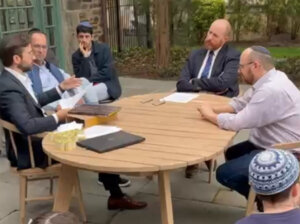 Rabbi Itamar Rosensweig, left, goes over the details of the contract with Nate Oman, center, while Chaim Saiman, right, listens in.