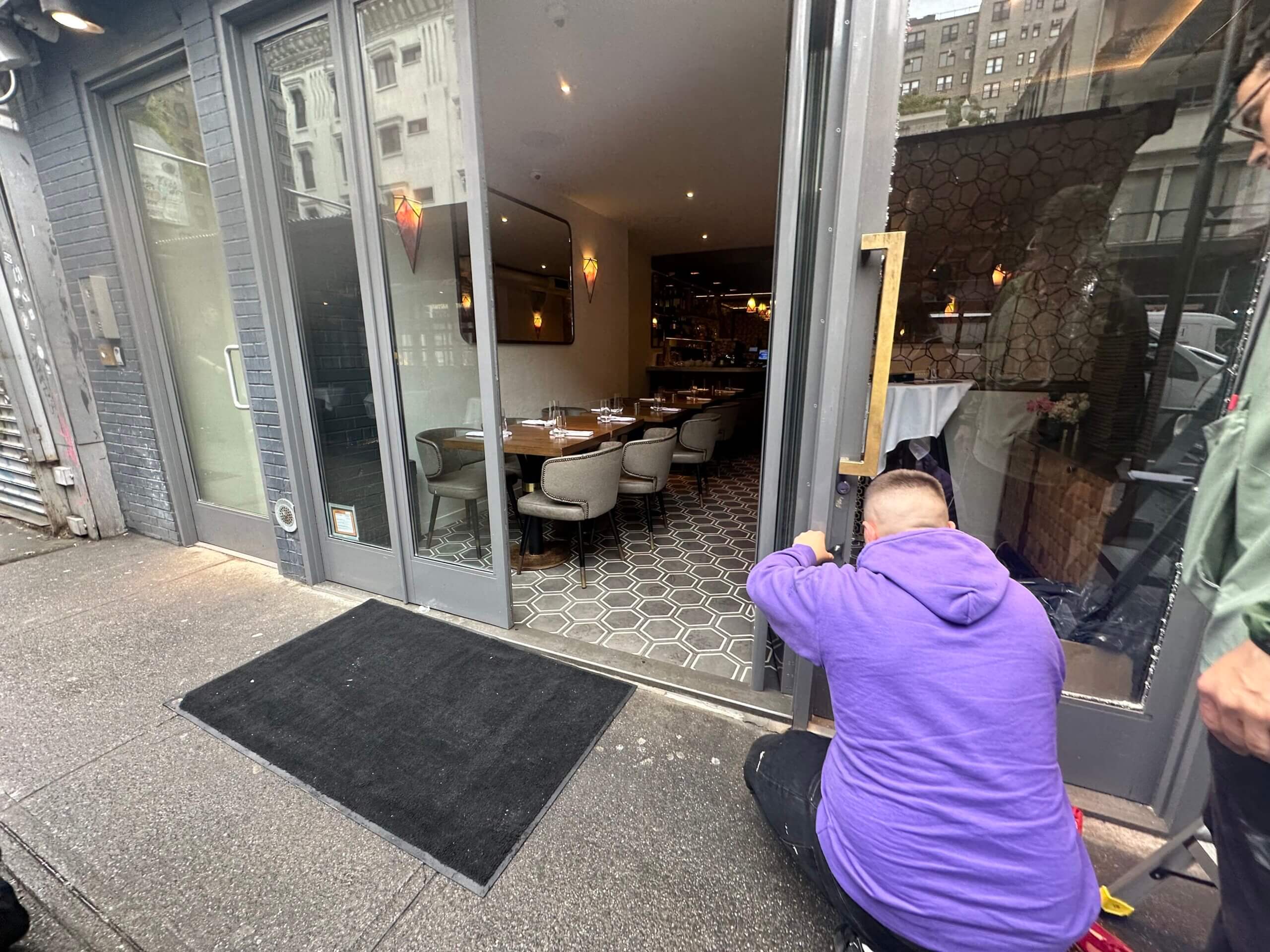 A worker cleans up broken glass in front of Rothschild TLV after it was vandalized.