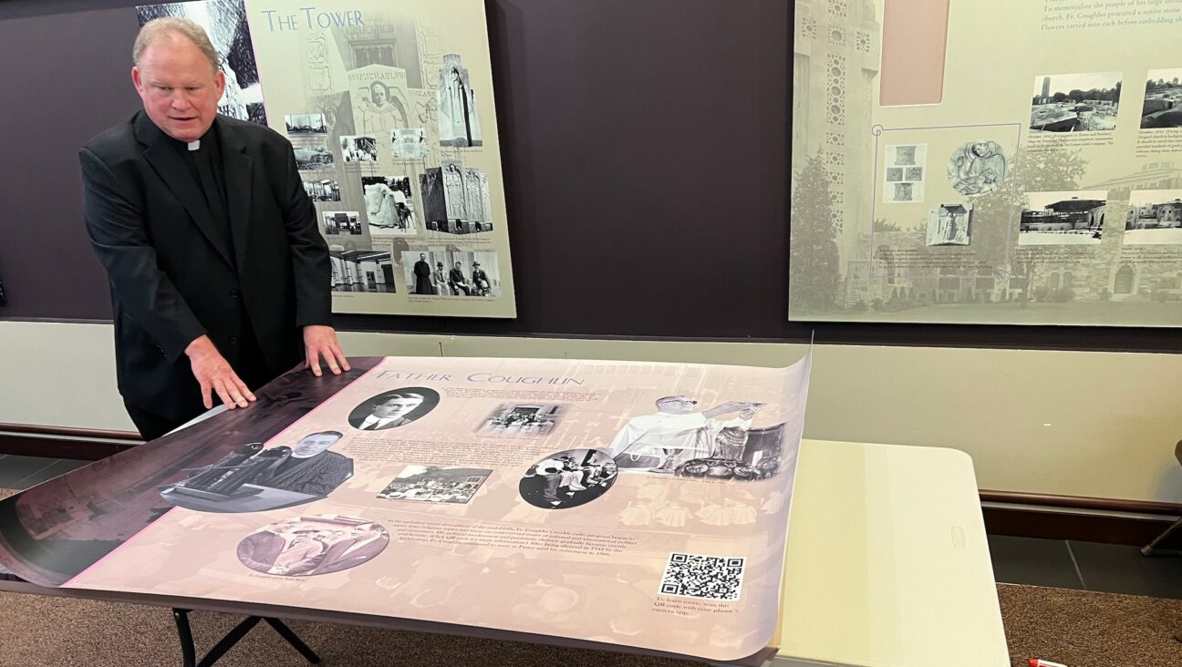 Rev. John Bettin, head pastor at the National Shrine of the Little Flower Catholic parish, prepares to mount a revised version of the church’s history of its antisemitic founder Father Charles Coughlin, Royal Oak, Michigan, Nov. 7, 2023. The new version includes a QR code for visitors to learn more about Coughlin’s antisemitism. (Courtesy of Levi Smith)