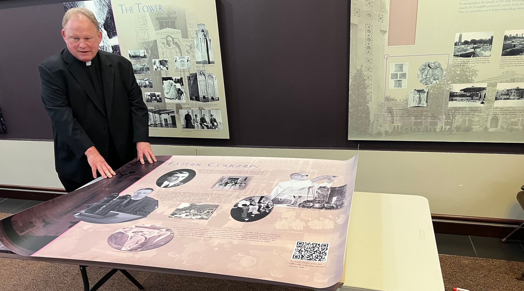 Rev. John Bettin, head pastor at the National Shrine of the Little Flower Catholic parish, prepares to mount a revised version of the church’s history of its antisemitic founder Father Charles Coughlin, Royal Oak, Michigan, Nov. 7, 2023. The new version includes a QR code for visitors to learn more about Coughlin’s antisemitism. (Courtesy of Levi Smith)