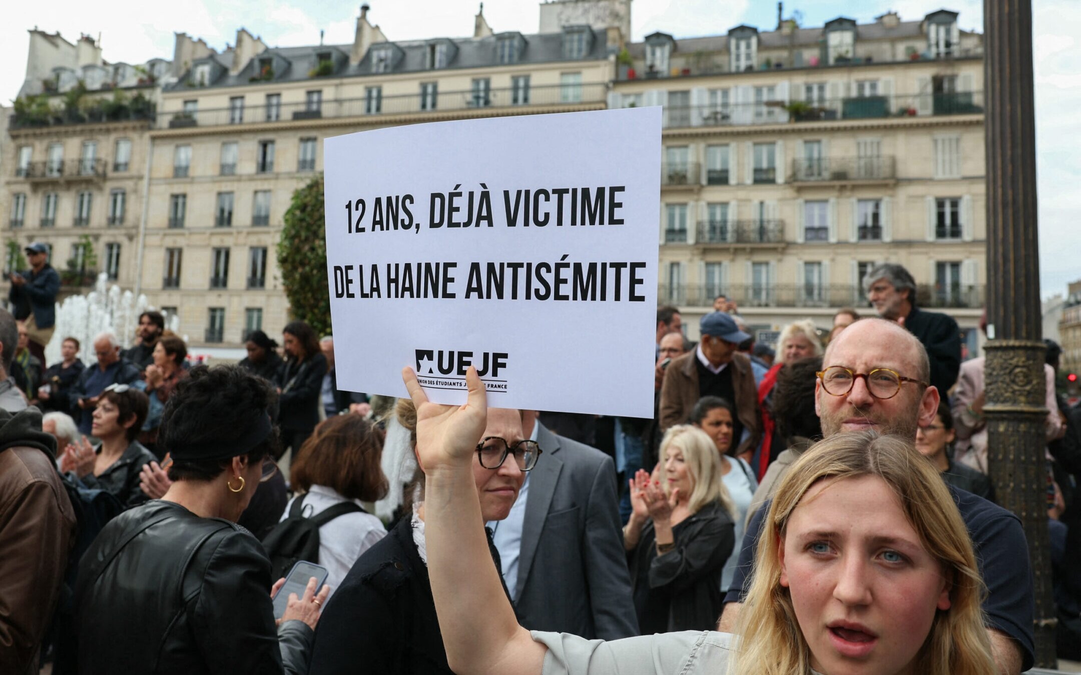 A protester holds a placard which reads as “Twelve-year-old and already a victim of antisemitic hate” as she gathers to condemn the alleged antisemitic gang rape of a 12-year-old girl, at the Paris City Hall square, June 19, 2024. Alain Jocard/AFP via Getty Images)