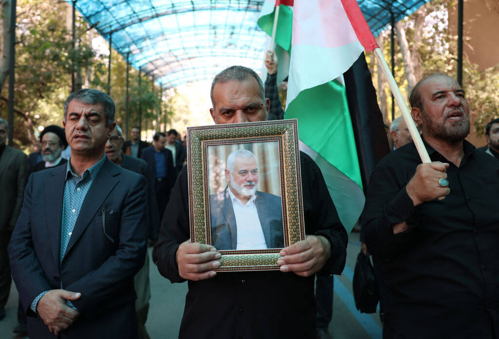 People hold up the Palestinian flag and a portrait of assassinated Hamas chief Ismail Haniyeh Hamas, during a rally at Tehran University, on July 31.