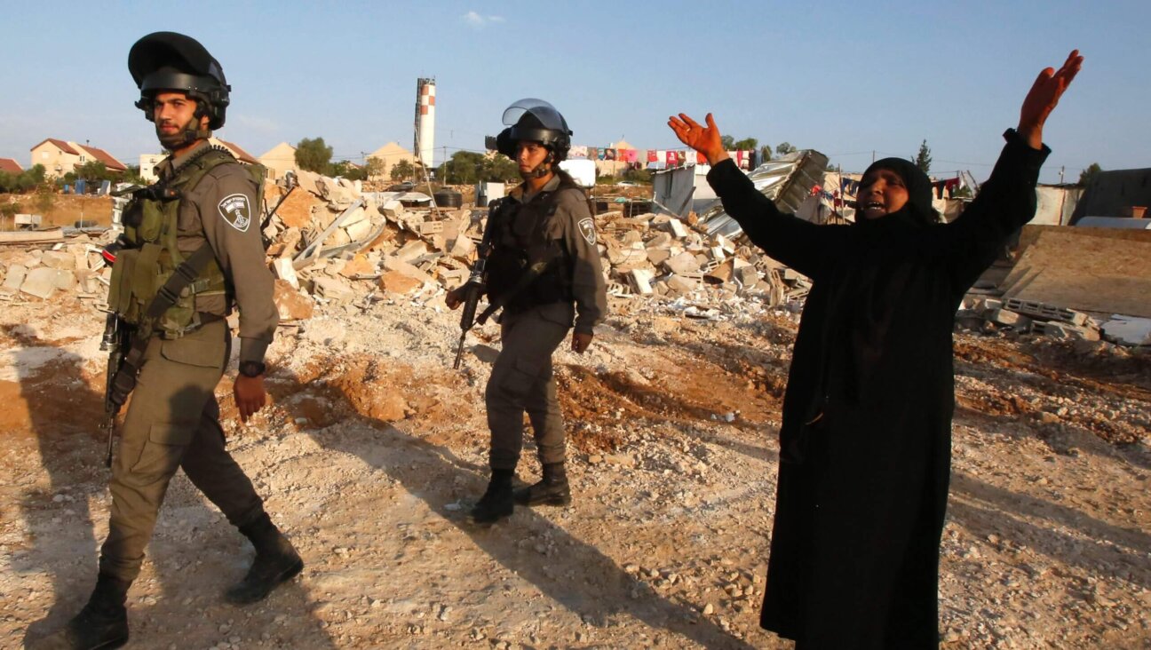 A Palestinian woman reacts as Israeli bulldozers destroy her home and a community center in the West Bank village of Umm al-Kheir, August 24, 2016.