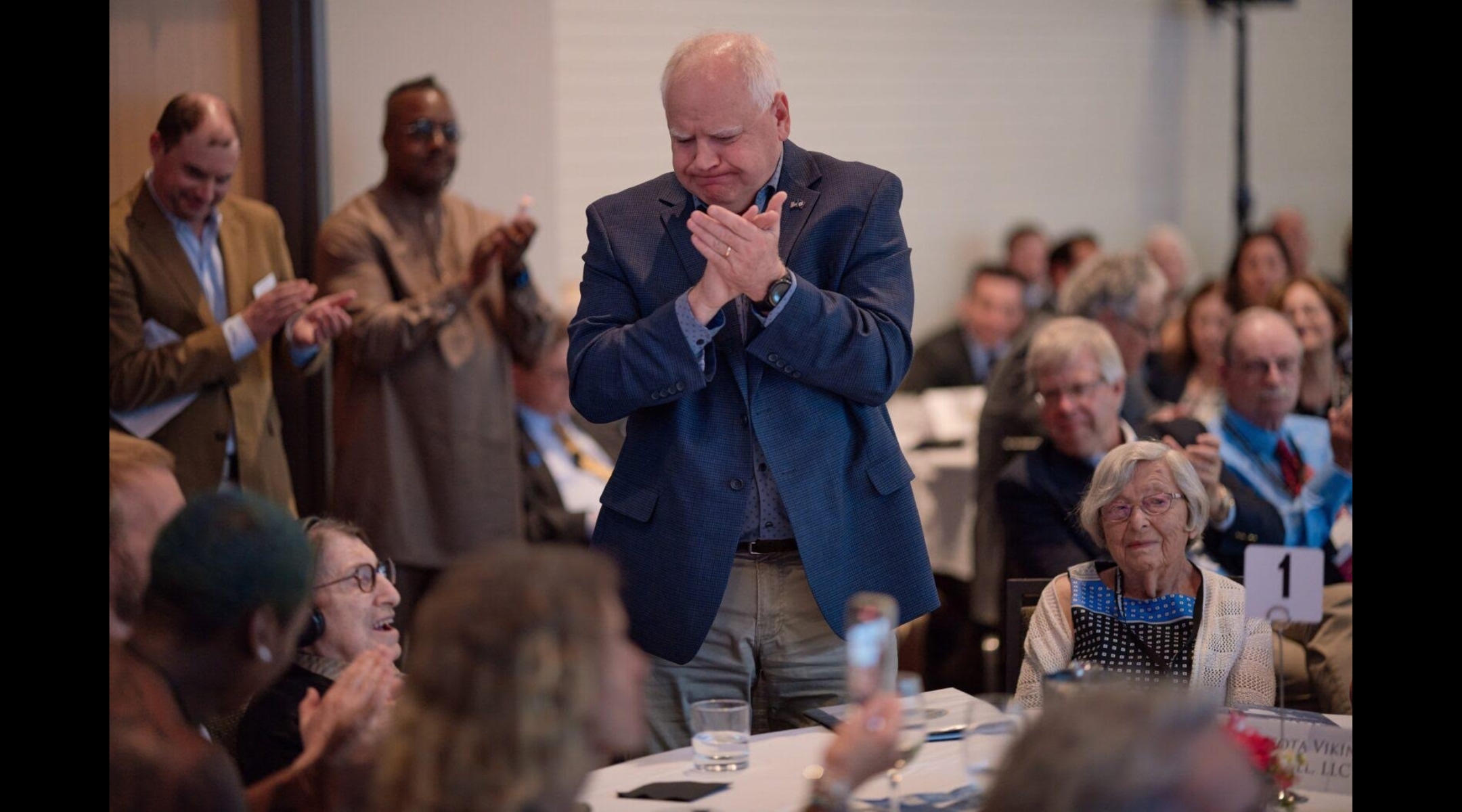 Holocaust survivor and education activist Dora Zaidenweber, (seated left) is given a standing ovation by Minnesota Gov. and Democratic vice presidential nominee Tim Walz (center) in June 2023. (Darrell Owens Photography)