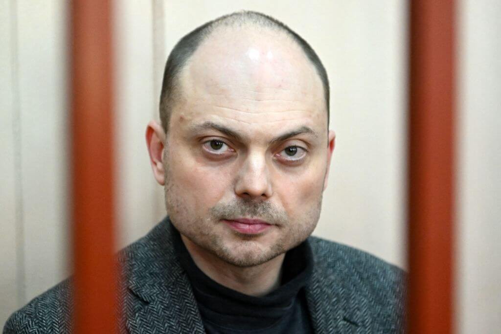 Russian opposition activist Vladimir Kara-Murza sits on a bench inside a defendants' cage during a hearing at the Basmanny court in Moscow on Oct. 10, 2022.