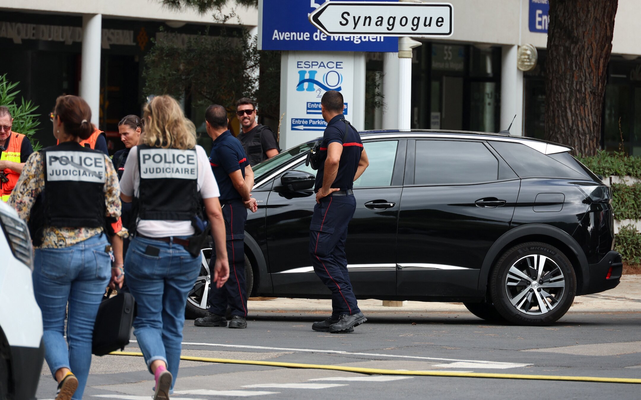 French judicial police officers walk past firefighters following a fire and explosion of cars at a synagogue in La Grande-Motte, south of France, Aug. 24, 2024. (Pascal Guyot/AFP via Getty Images)