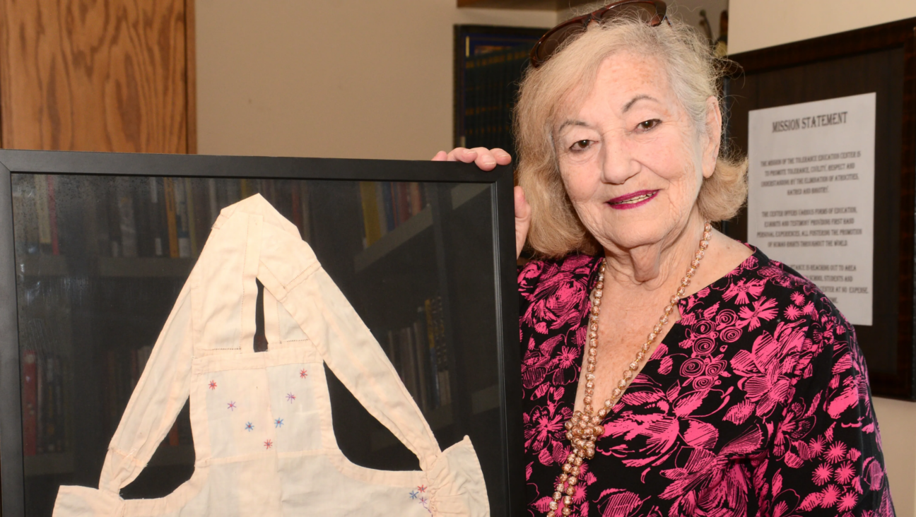 Holocaust survivor Goldie Jacoby holds an apron her mother made for her 6th birthday while the family was hiding in a barn to survive the Holocaust. (Courtesy/Blue Card)