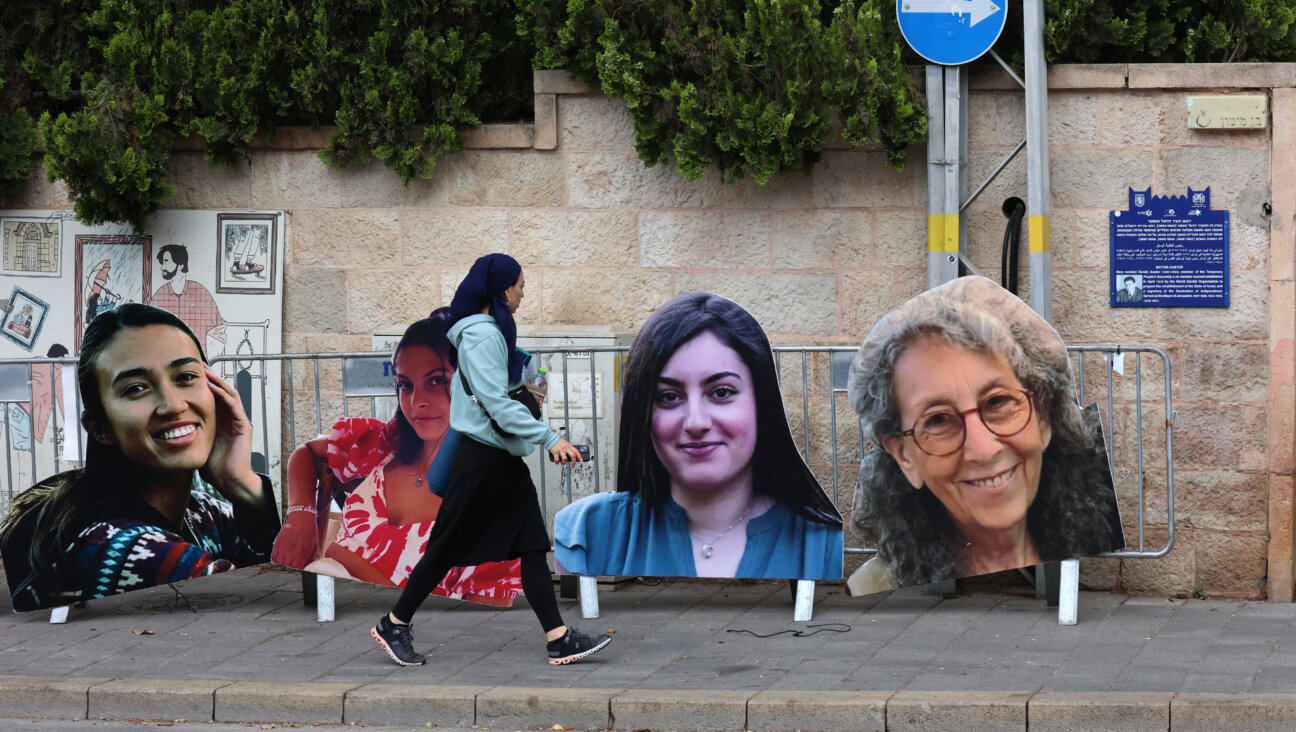 A woman walks past large cardboard cutout portraits of Israeli women held hostage in Gaza since the October 7 attacks, set up by relatives and supporters during a protest calling for their release in front of the Prime Minister's residence in Jerusalem.  