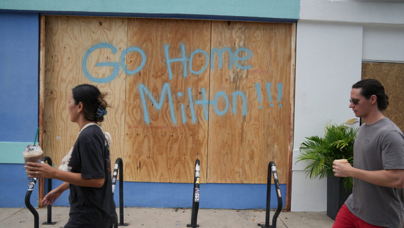 People walk past boarded up storefronts in Tampa, Florida, ahead of Hurricane Milton’s expected landfall, Oct. 8, 2024. (Bryan Smith/AFP via Getty Images)