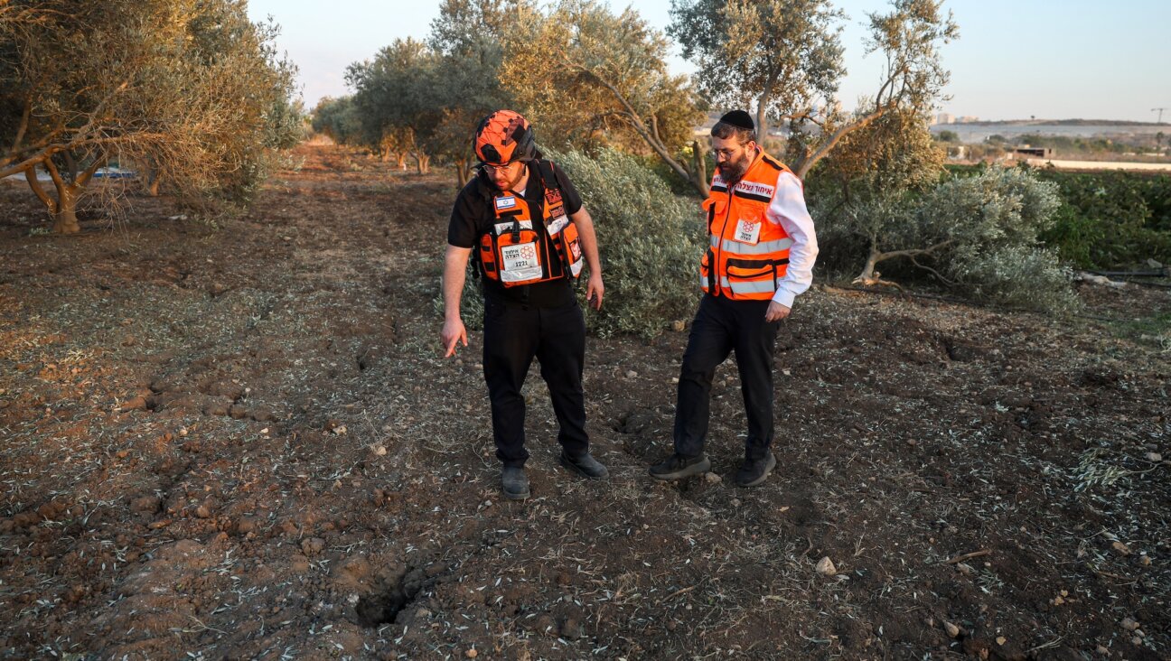 First responders stand next to a crater where a rocket fired from Lebanon hit an area in northern Israel’s Haifa district on October 31, 2024 (Ahmad Gharabli/ AFP)