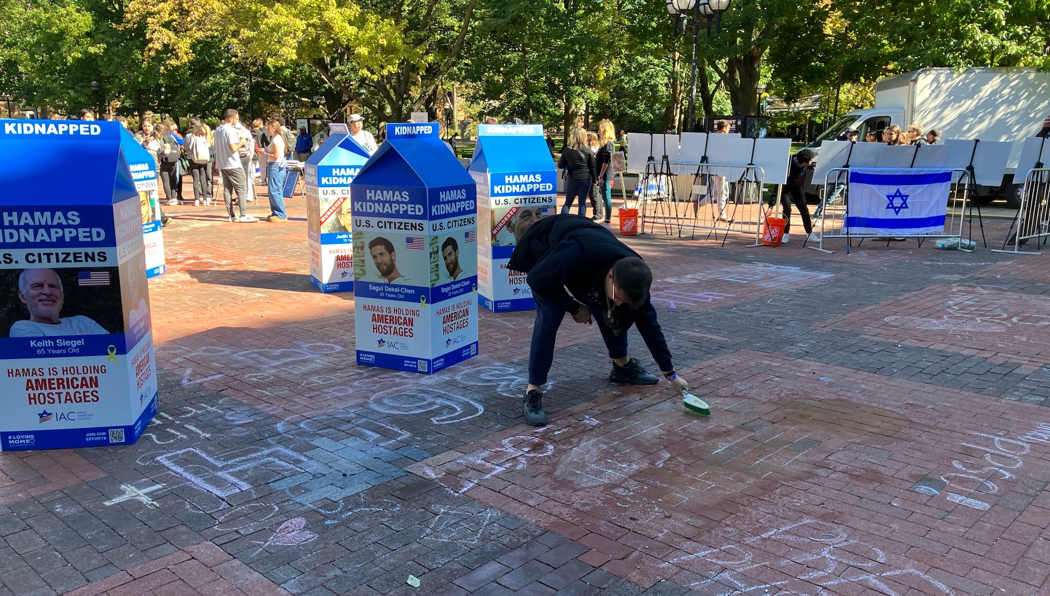 Pro-Palestinian chalk messages were briefly scrawled around a display of Israeli hostages in Gaza at the University of Michigan, Oct. 7, 2024, until Jewish students scrubbed them away. (Andrew Lapin)