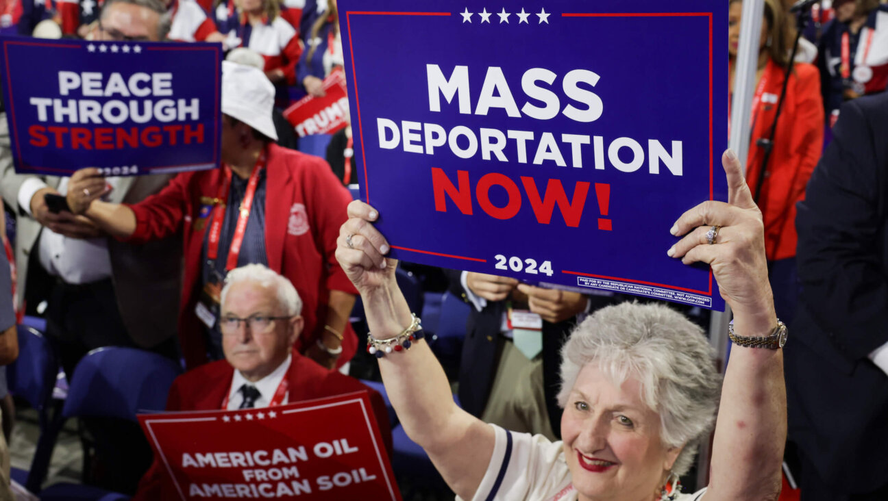 Attendees at the 2024 Republican National Convention hold signs reading "Mass Deportation Now!" 