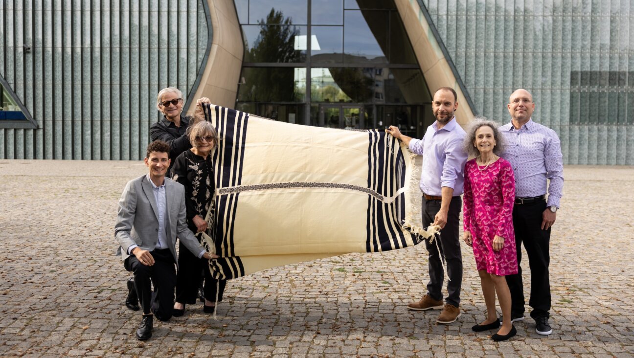 Lang family cousins hold Max Lang’s tallis in front of the POLIN Museum in Warsaw, on the day that they donated the prayer shawl to the museum. On the left, Stuart Schear (at rear), Jessie Lang and Jon Hanford. On the right, Theodore Hautin (holding the tallis), Annie Lang and Raphael Hautin. (Maciek Jazwiecki for POLIN Museum)