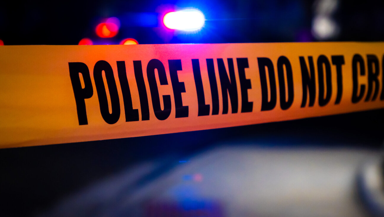 Police tape stretching across a road in front of a crime scene. (Getty Images)