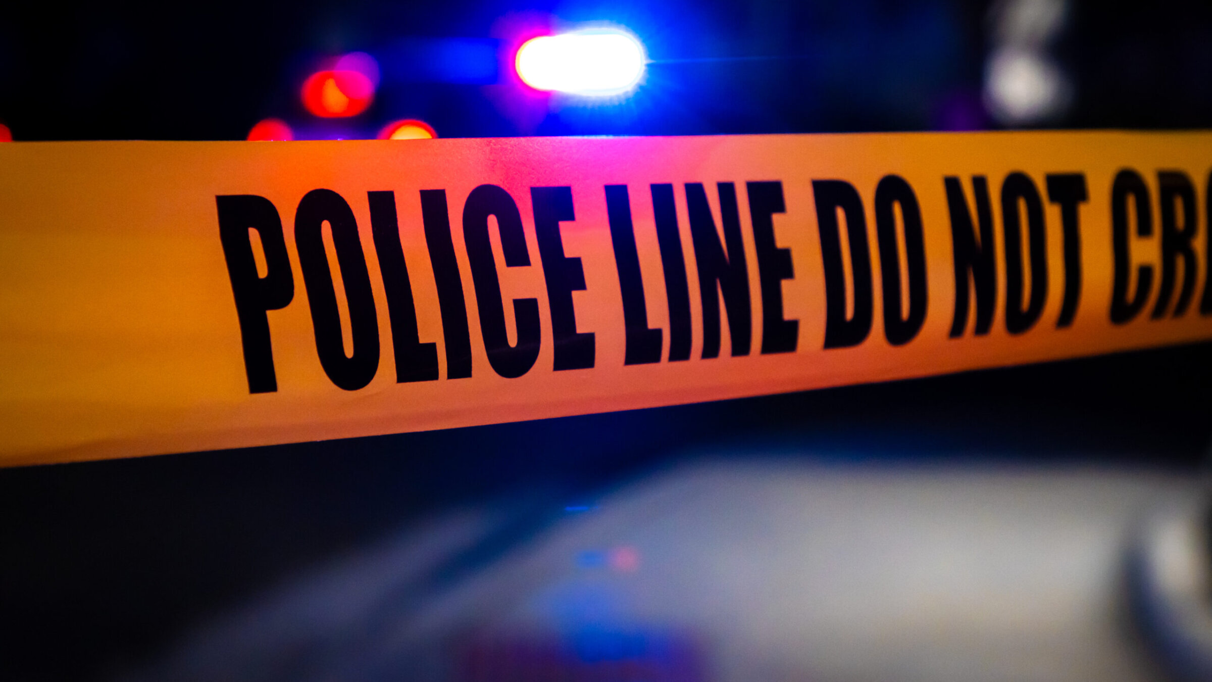 Police tape stretching across a road in front of a crime scene. (Getty Images)