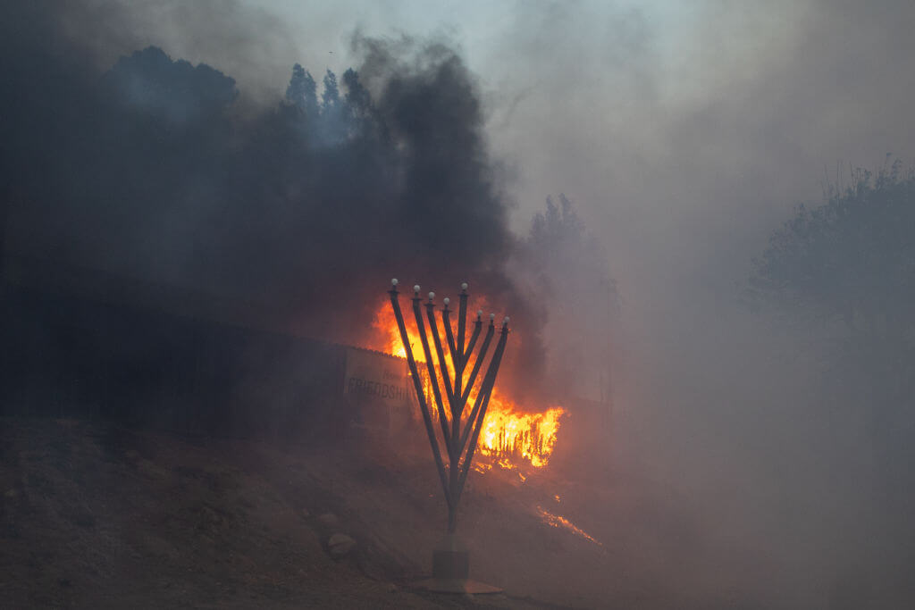 Flames from the Palisades Fire burn in front of the Jewish Temple Chabah of Pacific Palisades in Los Angeles, California. 