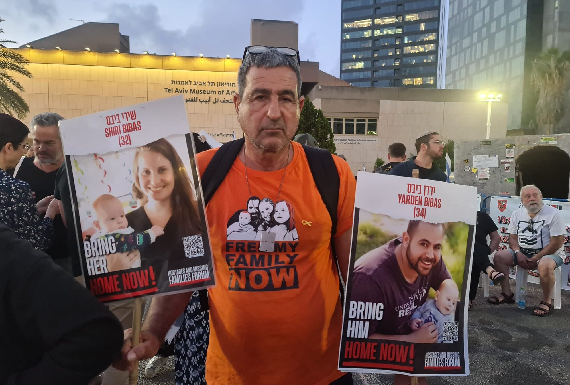 Eli Bibas holds pictures of his grandsons, who remain hostages in Gaza, during a pre-Passover rally in Tel Aviv. (Deborah Danan)