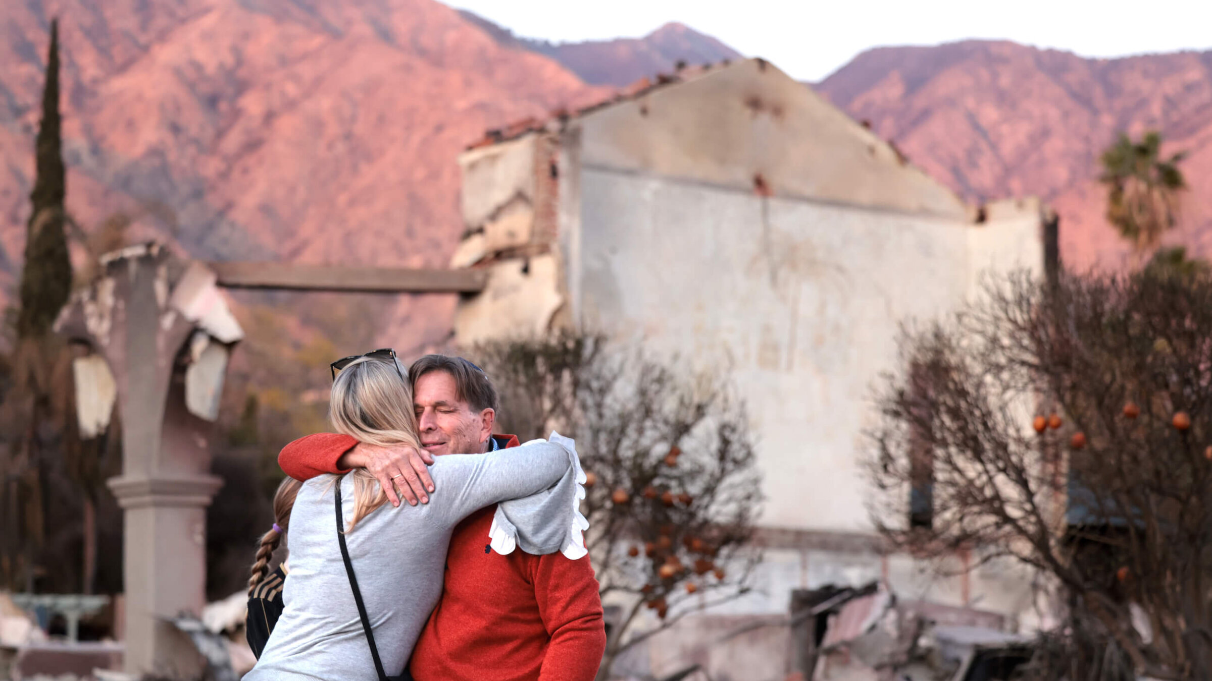 Congregants hug in front of what's left of the Pasadena Jewish Temple and Center after it was destroyed by the Eaton Fire.