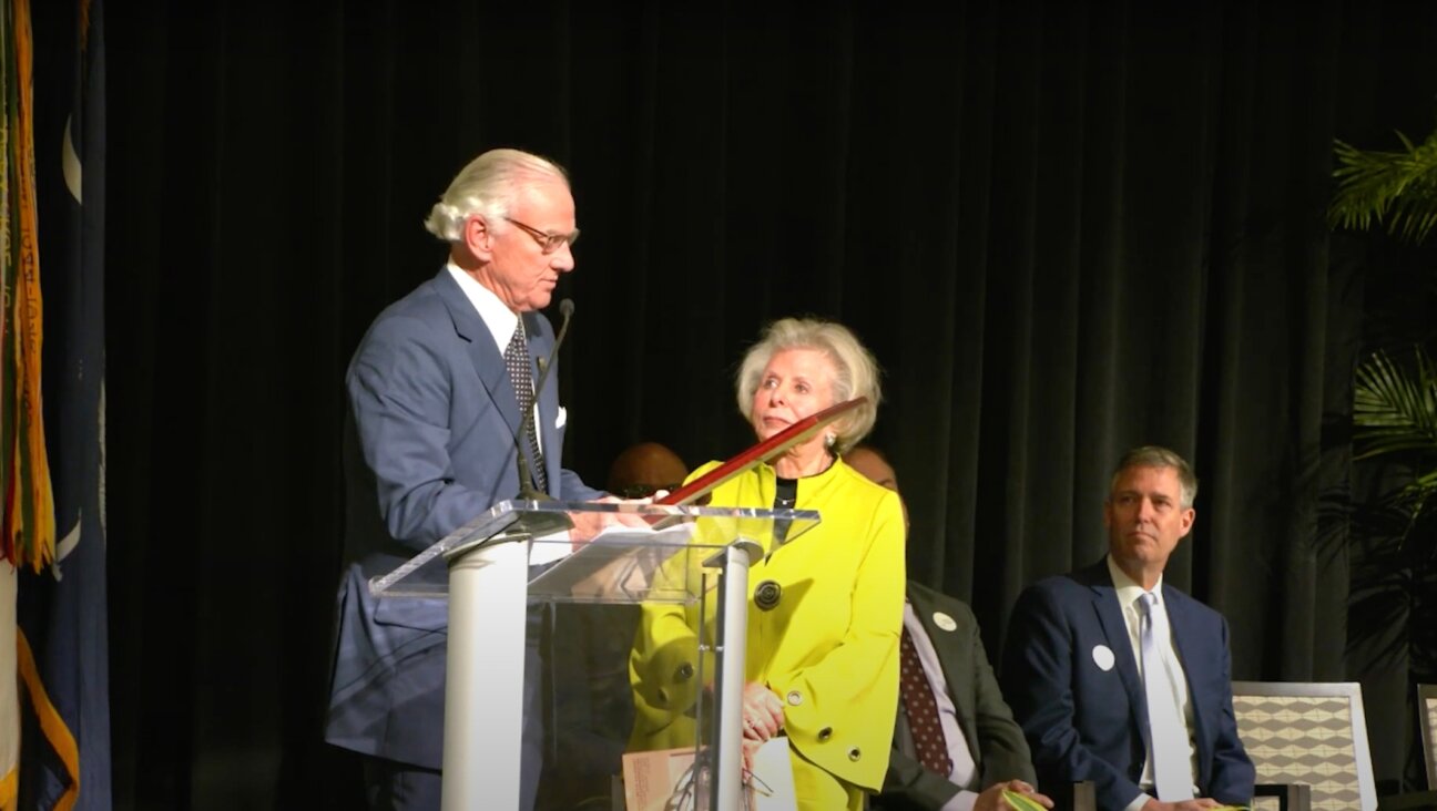 Lilly Filler (center), chair of the South Carolina Council on the Holocaust, accepts a state proclamation from Governor Henry McMaster recognizing the Holocaust during an event commemorating the 80th anniversary of the liberation of Auschwitz, Jan. 27, 2025, in Columbia, South Carolina. Filler would later cut a speech by a rabbi from the broadcast. (Screenshot via YouTube)