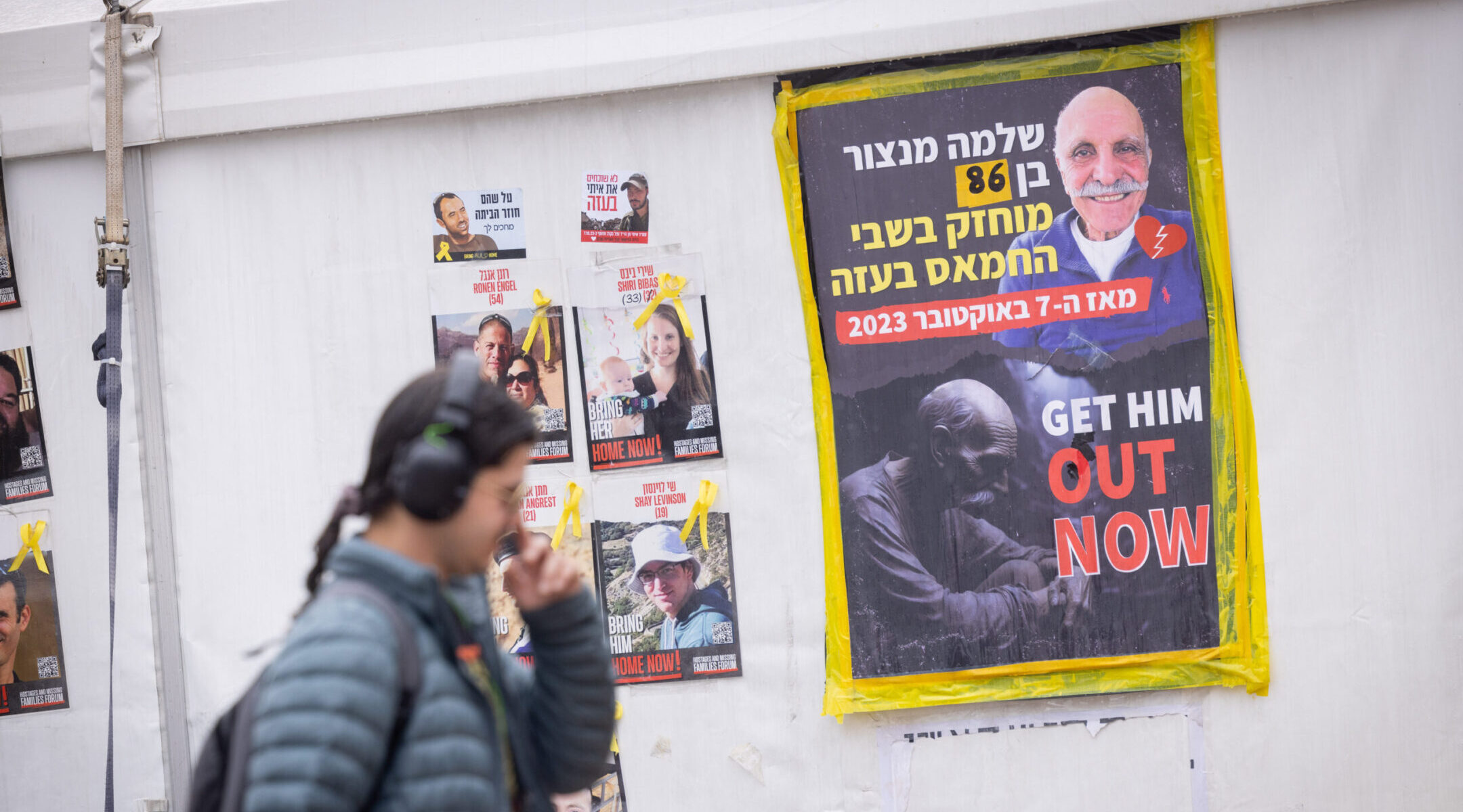 Visitors at Hostage Square in Tel Aviv pass a sign showing Shlomo Mansur, the oldest Israeli hostage in Gaza, Feb. 11, 2025. (Miriam Alster/Flash90)