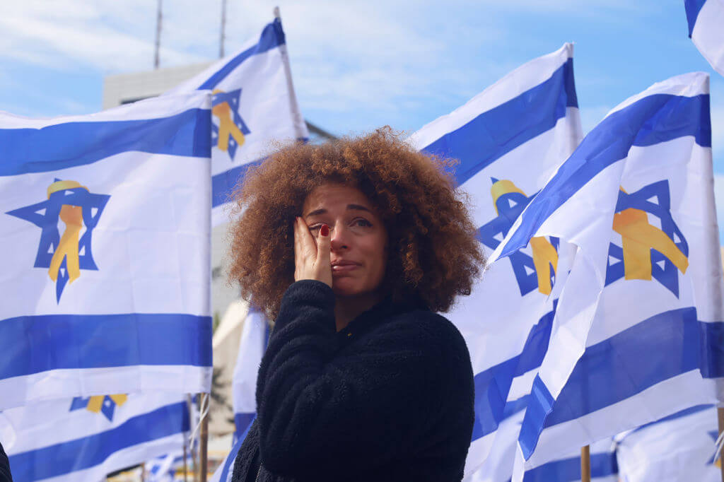 A woman cries as she stands among Israeli flags in Hostage Square in Tel Aviv prior the handover of four bodies taken by Hamas fighters on February 20, 2025.